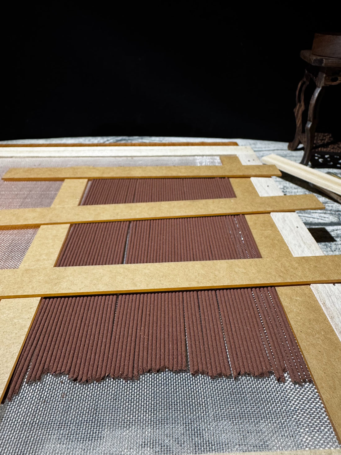 Natural botanical incense sticks resting on a wooden mesh drying rack in an artisan studio