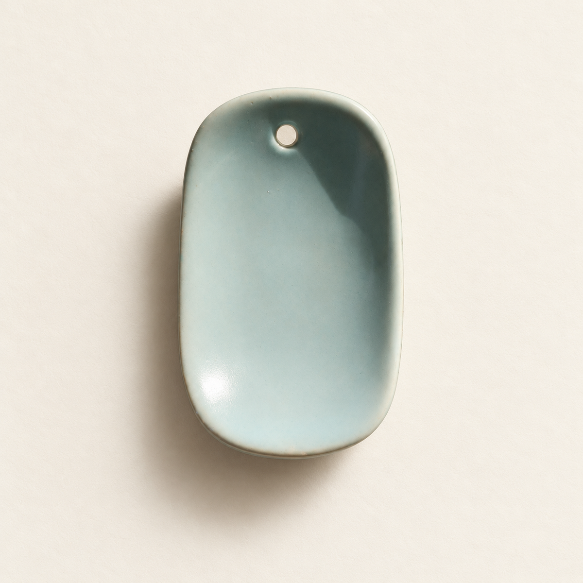 Front view of the celadon-green ceramic incense holder with a single incense-stick opening