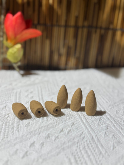 Upright and reclining handmade backflow incense cones on white fabric