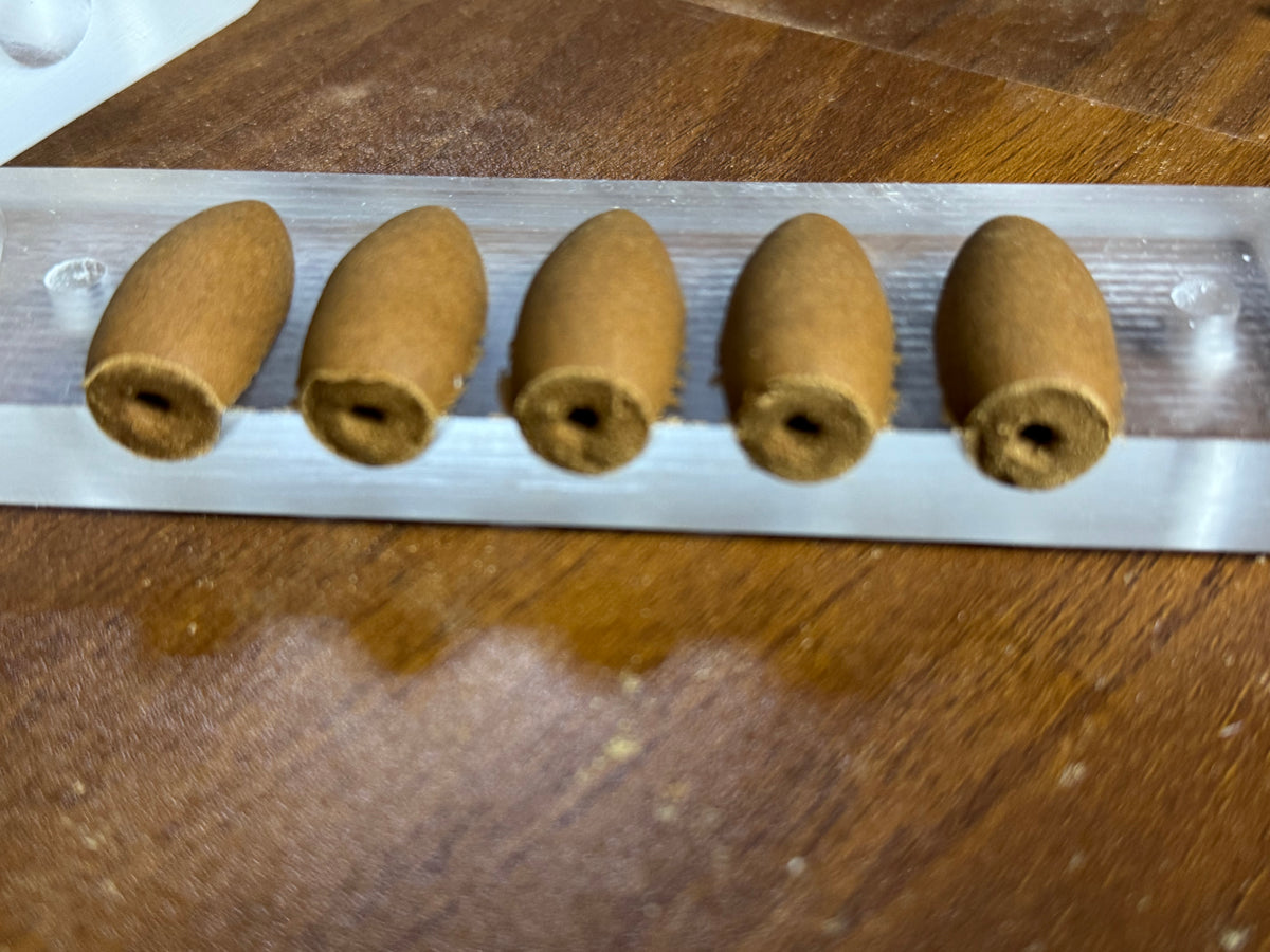 Handmade backflow incense cones in a mould showing the base openings