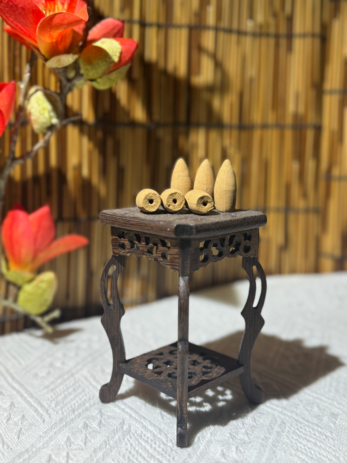 Backflow incense cones displayed on a carved wooden stand with a bamboo backdrop