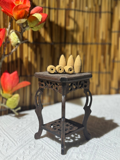 Backflow incense cones displayed on a carved wooden stand with a bamboo backdrop